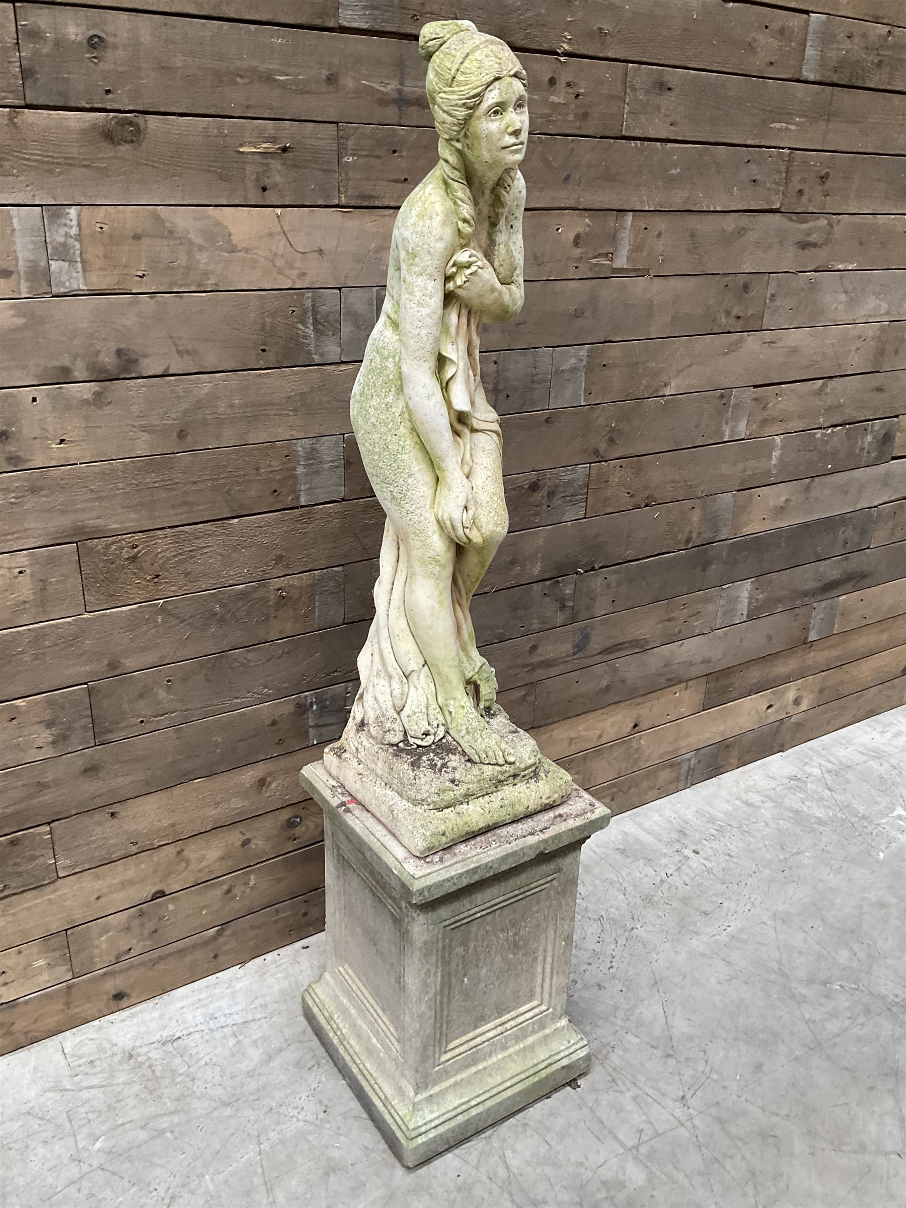 Cast stone garden figure of a bathing lady, raised on square plinth