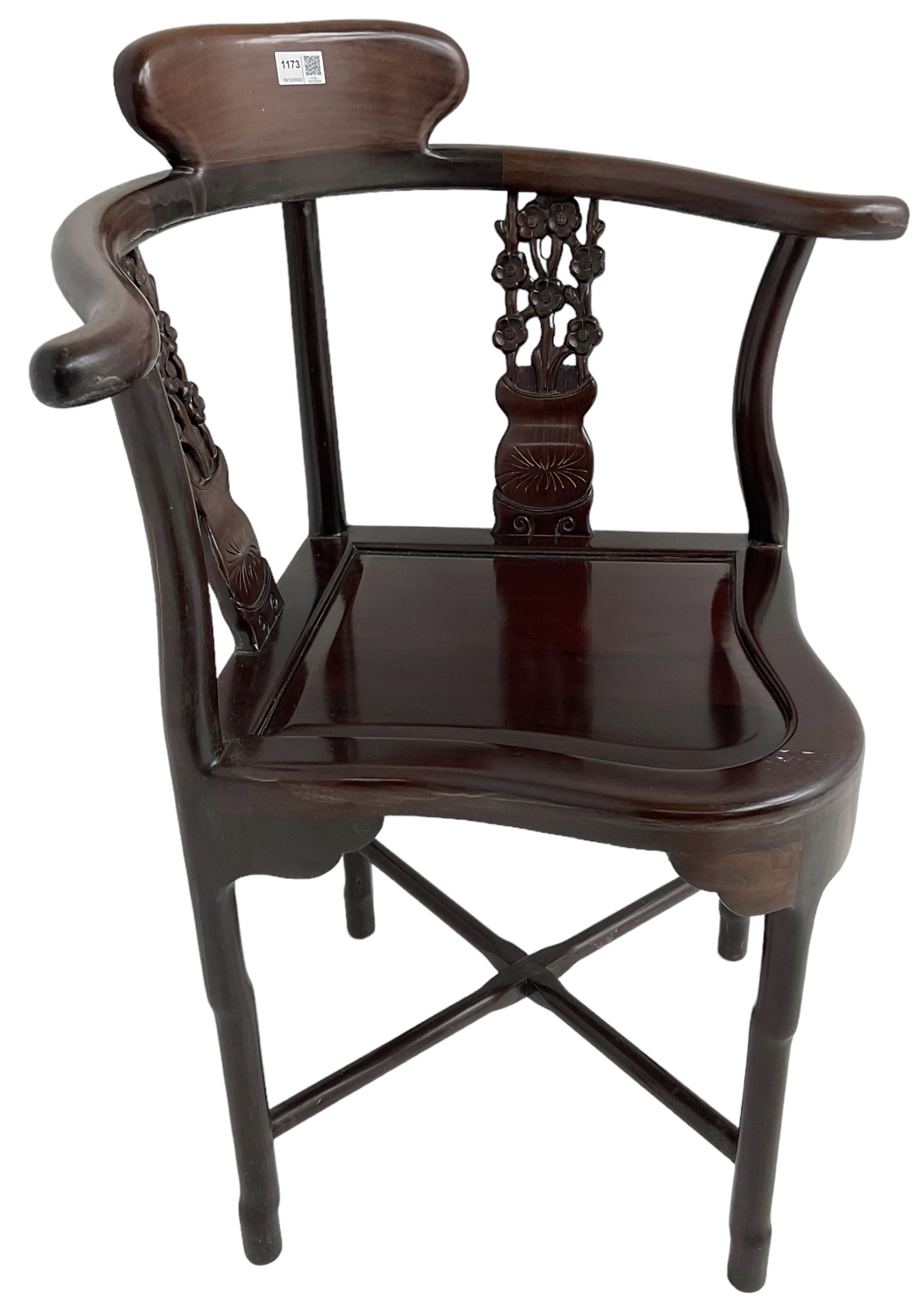 Chinese carved hardwood corner chair, outswept arms over pierced and carved floral splats, raised on shaped cylindrical supports united by X-stretcher