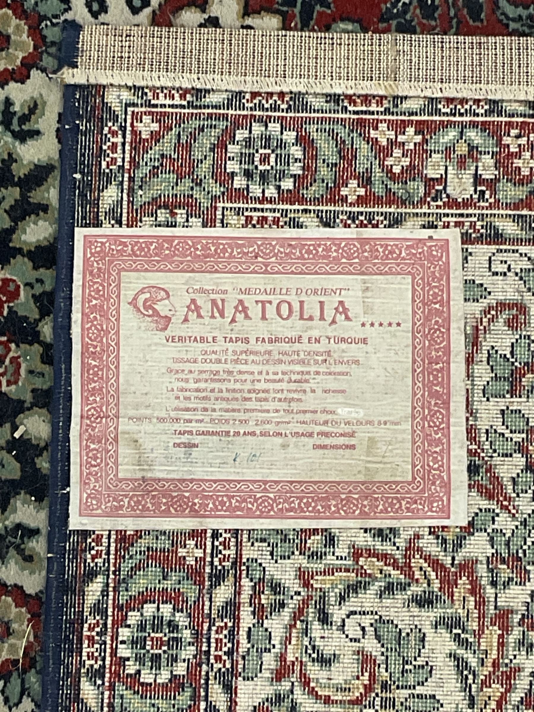 Persian design crimson ground carpet, the central rosette medallion surrounded by scrolling leaves and flower heads, the spandrels decorated with floral design and scrolling foliage, repeating border within guard stripes