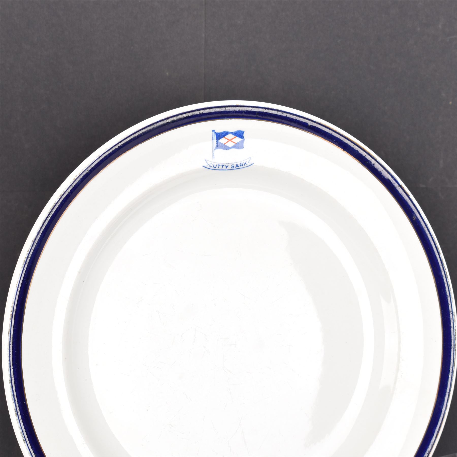 Early 20th century 'Cutty Sark' dinner plate, printed with the house flag and ship's name beneath, within a cobalt blue and gilt border upon a white ground, with printed maker's mark beneath for T. Hayward & Co, D24.5cm

Provenance by vendor repute: Vendor's father was a naval cadet in 1940s/50s on board HMS Worcester which was moored alongside the Cutty Sark on the River Thames at Greenhithe. He has had the plate since then. 