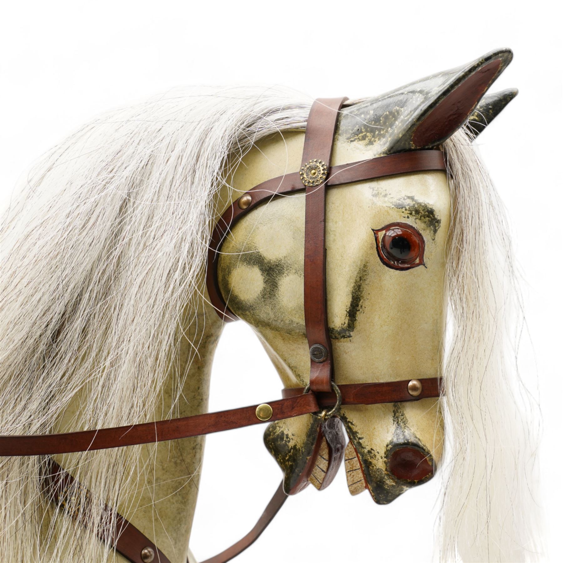 In the manner of F. H. Ayres - large carved wooden rocking horse, in dapple grey paint finish, decorated with glass eyes, leather reins, stirrup and saddle, on bowed rockers united by turned stretchers and boarded base 