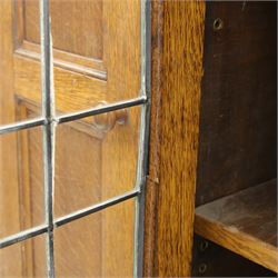 Edwardian oak glazed cabinet, moulded cornice above a panelled front and sides, fitted with lead glazed doors enclosing shelved interior, left side full length cupboard converted to enclose a gun cabinet, on a plain plinth base 