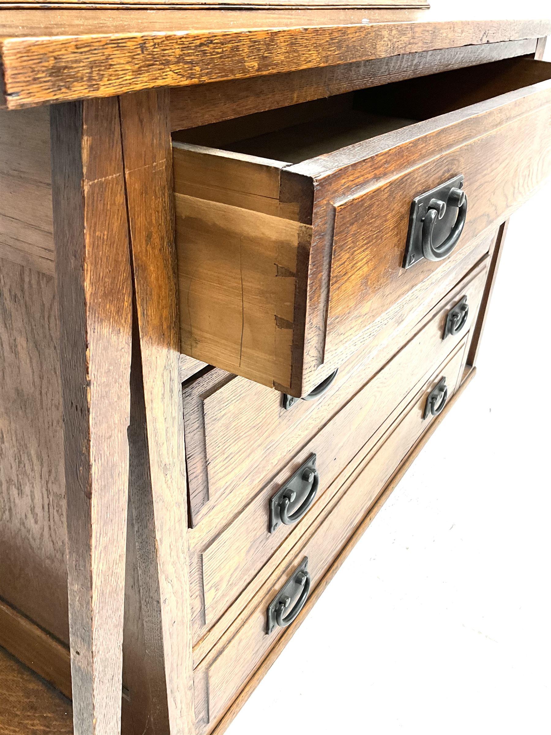 Arts & Crafts oak cabinet on chest, projecting cornice above to lead glazed cabinet doors, two shelves flanking single fall front enclosing fitted interior, four graduating drawers
