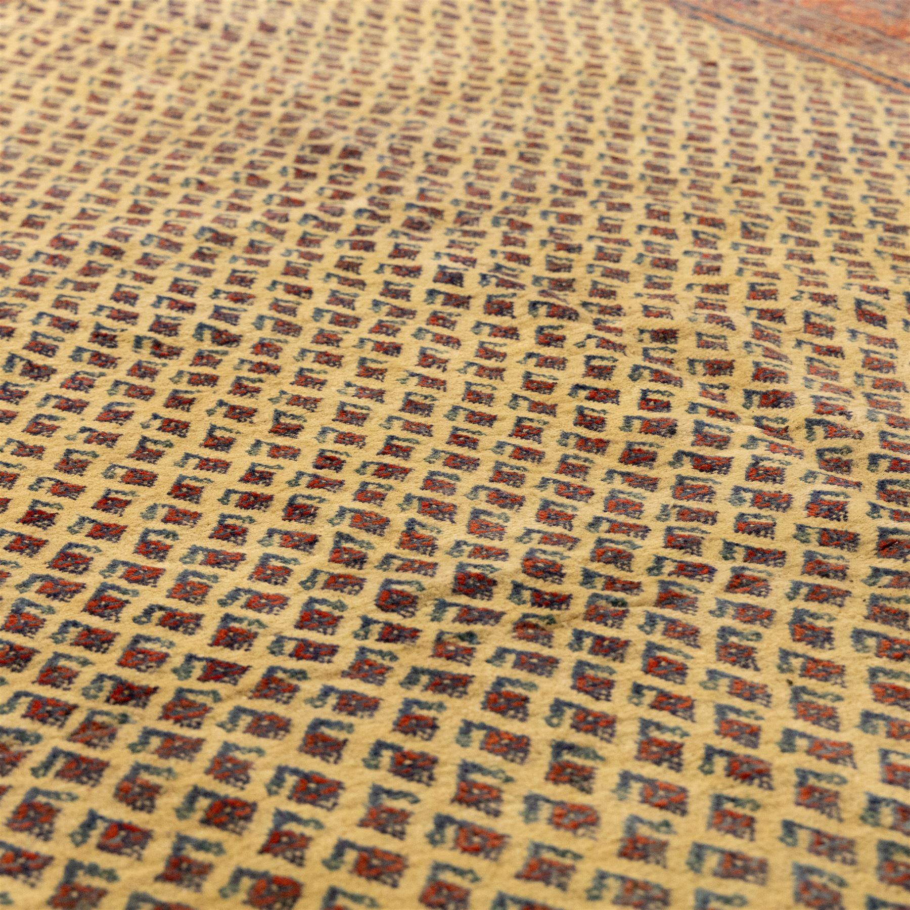 North West Persian Arak hand-knotted carpet, ivory ground densely decorated with an all-over diagonal boteh lattice design within a madder red main border of stylized rosettes and botehs between multiple narrow floral guard stripes