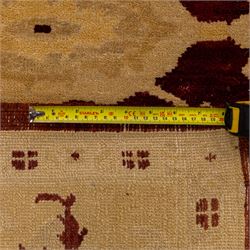 Ziegler design hand knotted wool rug, the rich red ground woven with oversized floral medallions and angular vine scrolls, framed by a contrasting ivory border of repeating floral ornament and minor guard stripes, with fringed ends