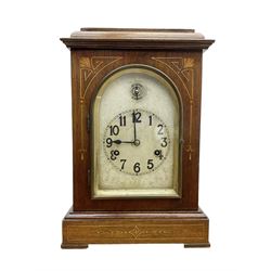 Edwardian - 8-day mantel clock in a mahogany case with satin wood inlay, flat toped case with an arched glazed door, silvered dial with engraving, Arabic numerals, minute track and steel spade hands, strike/silent feature to the arch, movement striking the hours and half hours on four gong rods.
With pendulum.