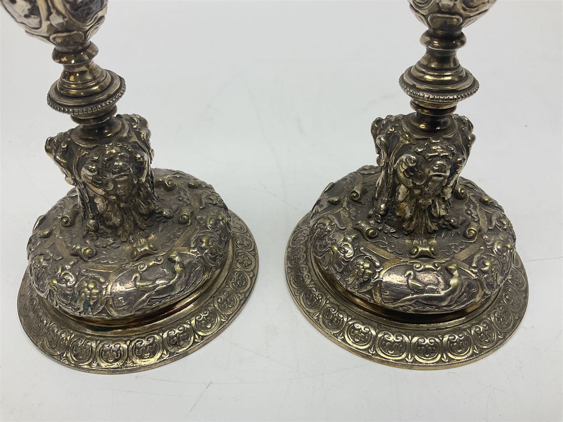 Pair of Victorian Elkington Mason & Co silver plated candlesticks, decorated in relief with ram masks and figures, H14cm