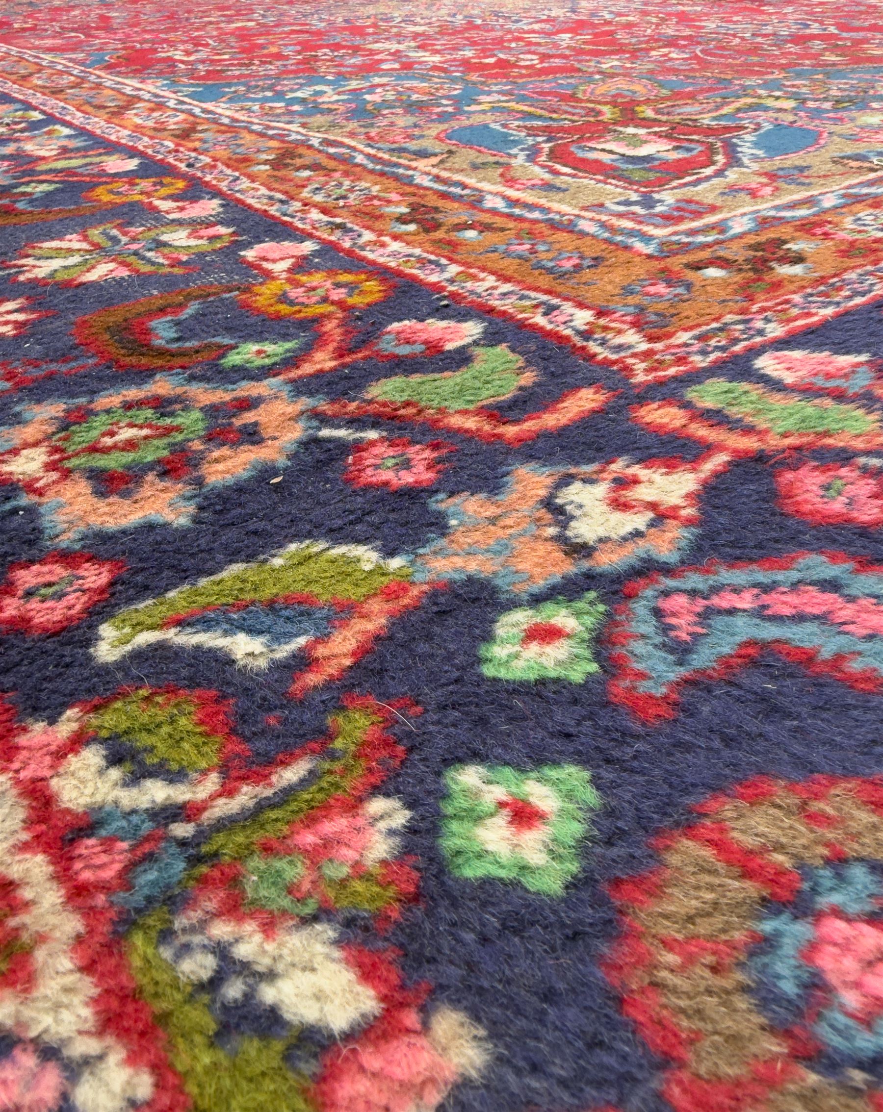 Pair of Persian wool rugs, each with rich red ground, one centred with a diamond-shaped medallion and navy spandrels within a floral field, the other with radiating floral medallion and scrolling foliate motifs, both enclosed by multiple borders with palmette and flowerhead designs, from the region of Kashan 291x376, 299 x 378 