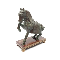 A bronze Tang style horse, modelled seated with one front leg raised, upon rectangular wooden base, bronze H20.5cm. 