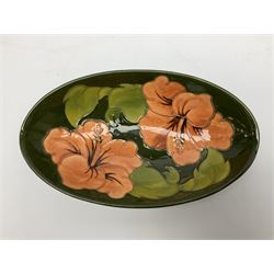 Moorcroft oval bowl, decorated in the Hibiscus pattern upon a green ground, with impressed marks and remnants of paper label beneath, L23cm