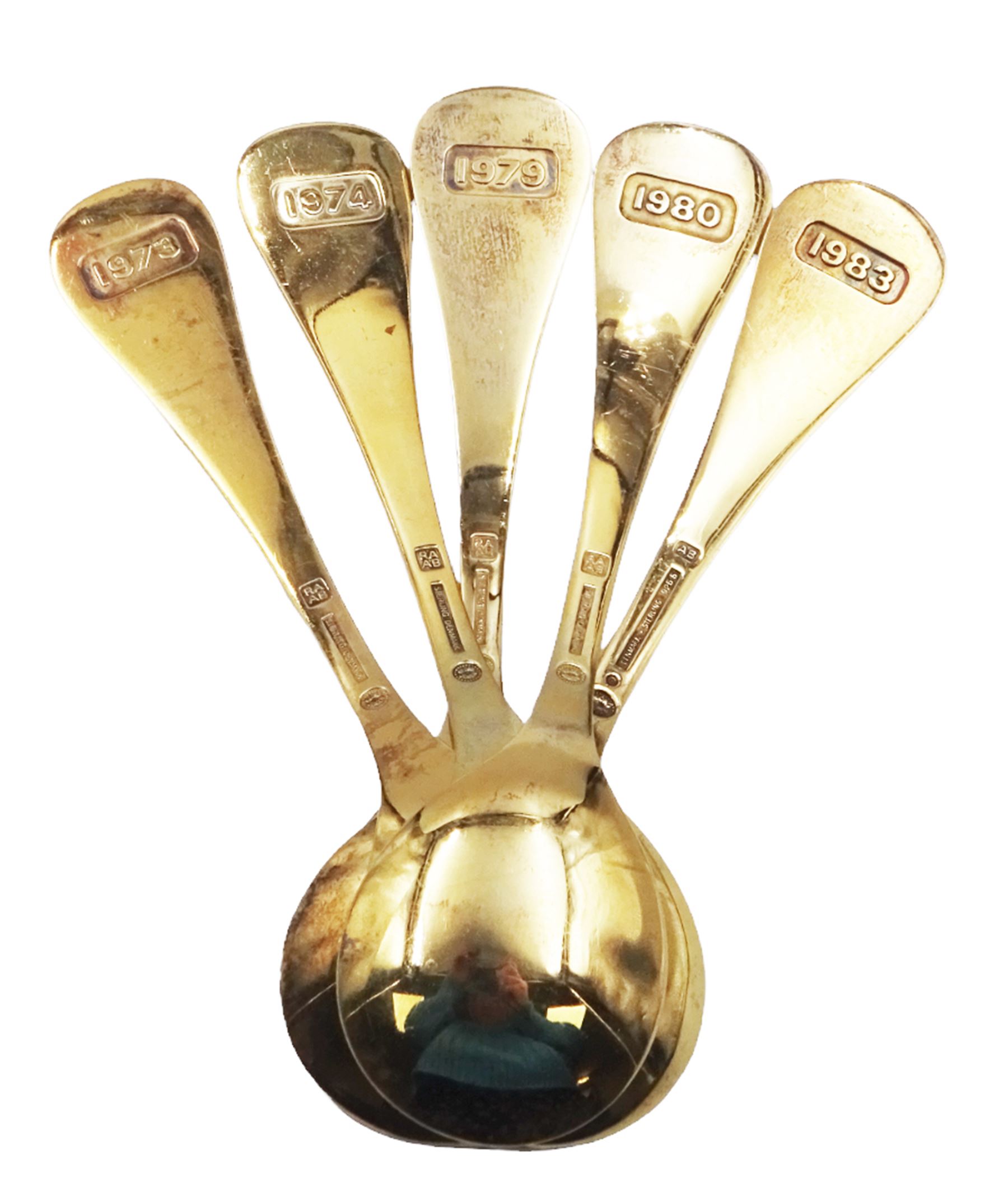 Five Danish silver-gilt year spoons by Georg Jensen, each decorated with different floral motif including sunflower, forget-me-not and shamrock, dated between 1973 and 1983, each impressed on underside RA AB, Sterling Denmark, and marked for Georg Jensen, approximate gross weight 7.3ozt (227 grams)