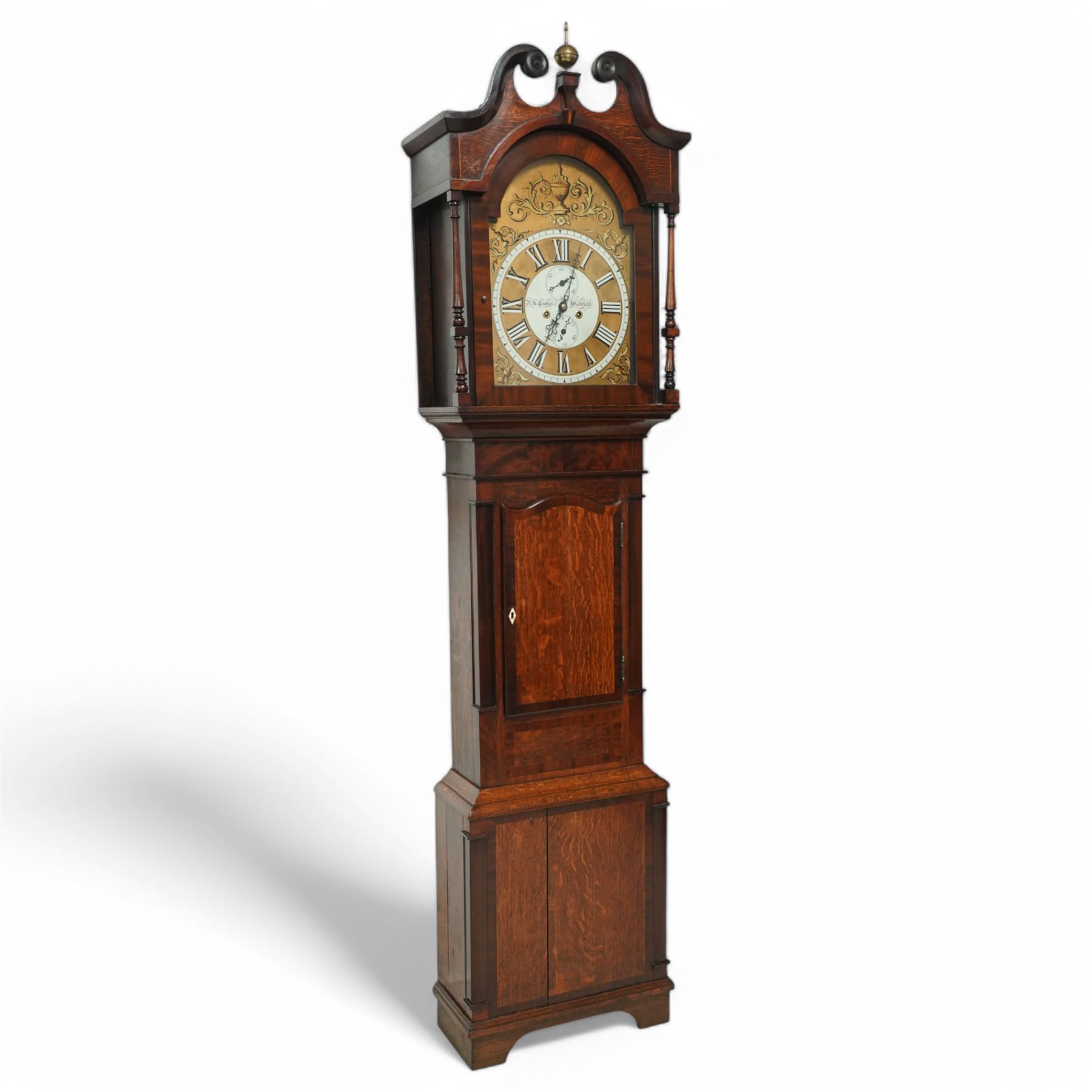 John Henry Coates of Wakefield- late19th century oak and mahogany 8-day longcase clock c 1860, with a swan necked pediment and central brass ball and spire finial, break arch hood door flanked by unusual turned pilasters, trunk with recessed rectangular corners and a wavy topped door, on a square plinth with conforming recessed corners and raised on a shaped base, fully painted dial with matching decorative rococo painted decoration to the spandrels and arch, with 