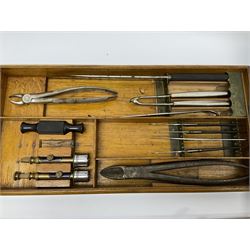 Naval doctor's surgical instruments, contained in a converted brass bound oak pistol box, the hinged lid opening to reveal two removable fitted trays, containing 19th century and later saws, scalpels, tweezers etc