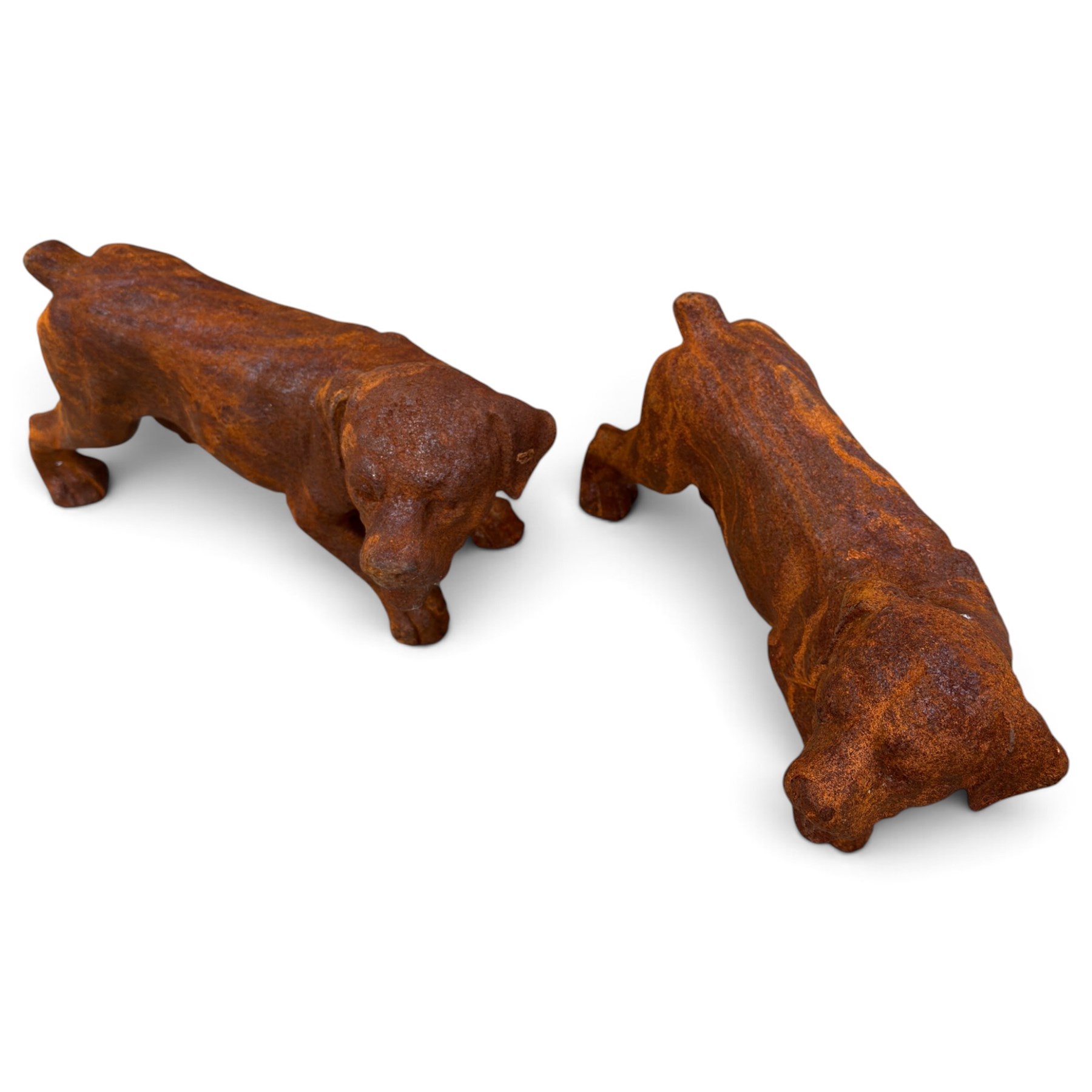Pair of weathered cast iron garden ornaments modelled as playful Rottweiler puppies, in rusted finish