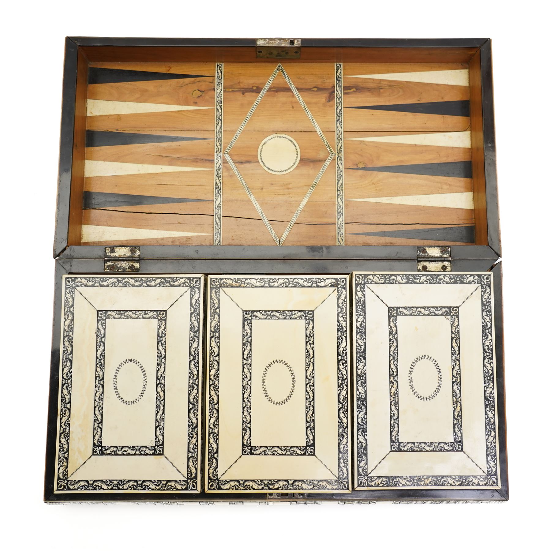 Mid-19th-century Anglo Indian Vizagapatam ivory, sandlewood, and horn veneered backgammon/chess board, circa 1860, rectangular games box the borders engraved with a stylized scrolling leaf decoration and spine engraved History of Persia the interior inlaid for backgammon, with three internal sandalwood boxes with covers, containing 16 ivory pieces and 16 horn pieces, comprising, kings and queens with pierced crowns on baluster carved shafts; bishops with carved mitres; knights represented by horses’ heads; and rooks as towers with imbricated decoration.

This item has been registered for sale under section 10 of the APHA Ivory Act, submission reference G68PNYA5 

