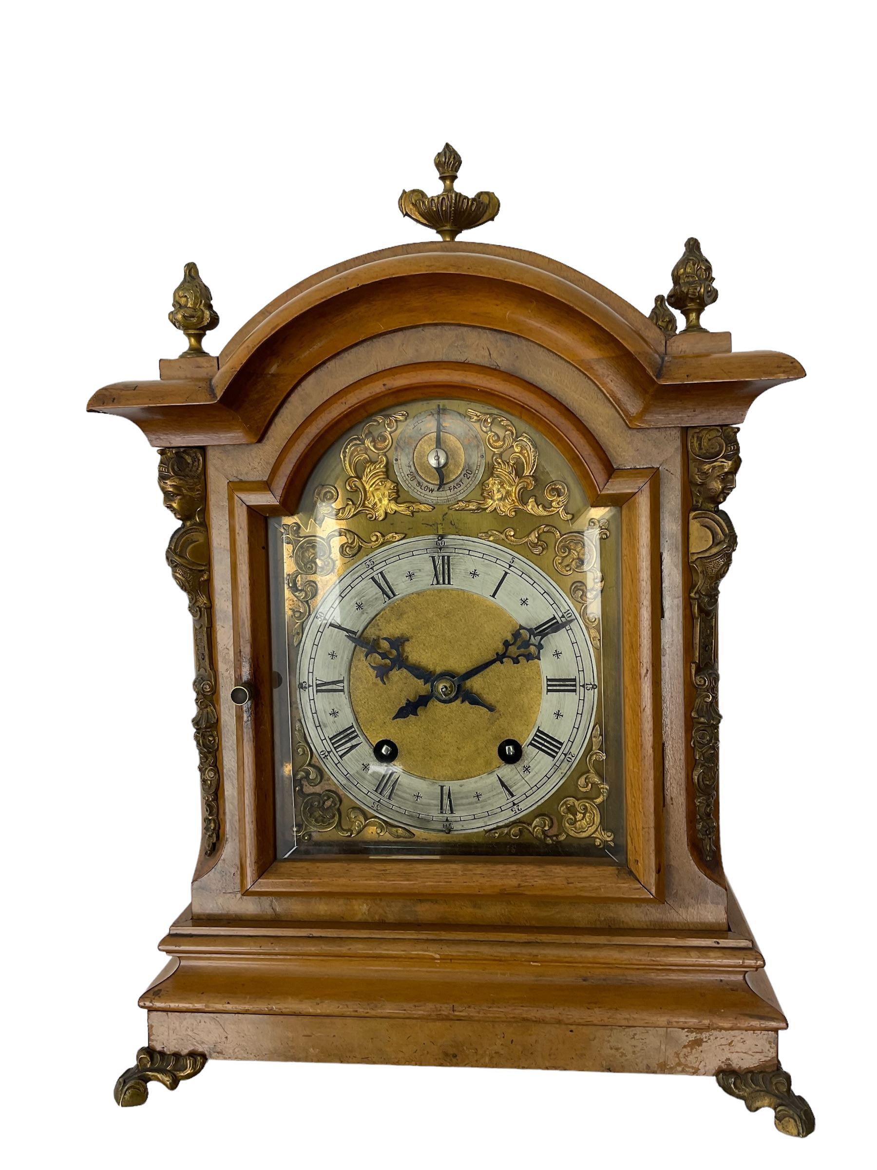 German - 19th century 8-day walnut bracket clock, striking the quarters on two coiled gongs, case with a break-arch top surmounted by cast brass finials, canted corners to the front with cast brass caryatids and sound frets to the sides, brass break arch dial with a silvered chapter ring, steel gothic hands, spandrels, and pendulum regulation dial. With pendulum.