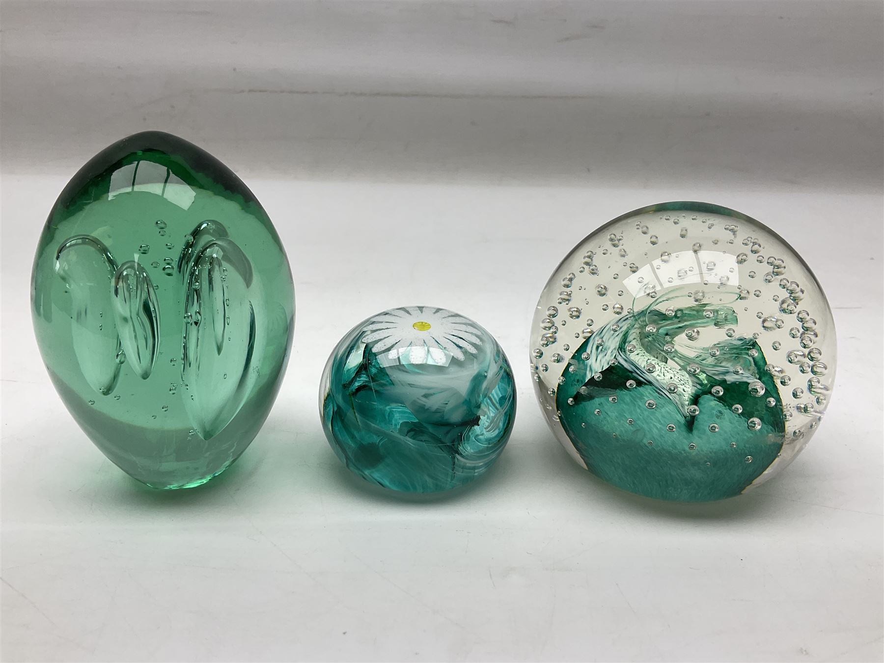 Three millefiori paperweights, together with a green glass dump paperweight with air bubble inclusions, Caithness Daisy and Cauldron paperweights and two small Caithness glass vases, tallest H9cm