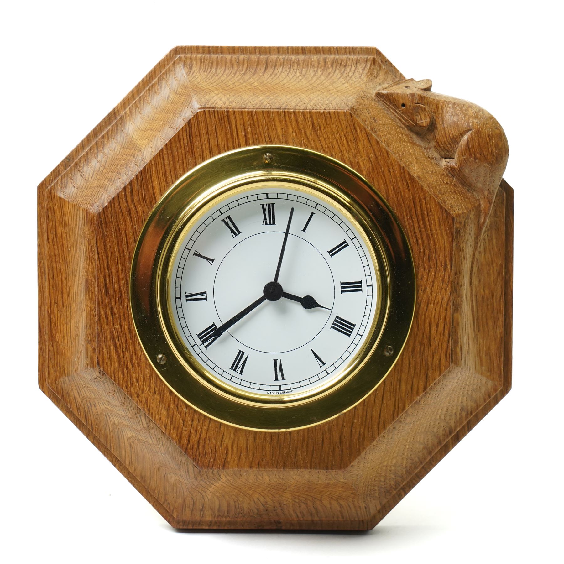 Mouseman - oak wall clock, circular Roman dial in brass drum on moulded octagonal mount, , fitted with battery operated Quartz movement, with carved mouse signature, by the workshop of Robert Thompson of Kilburn