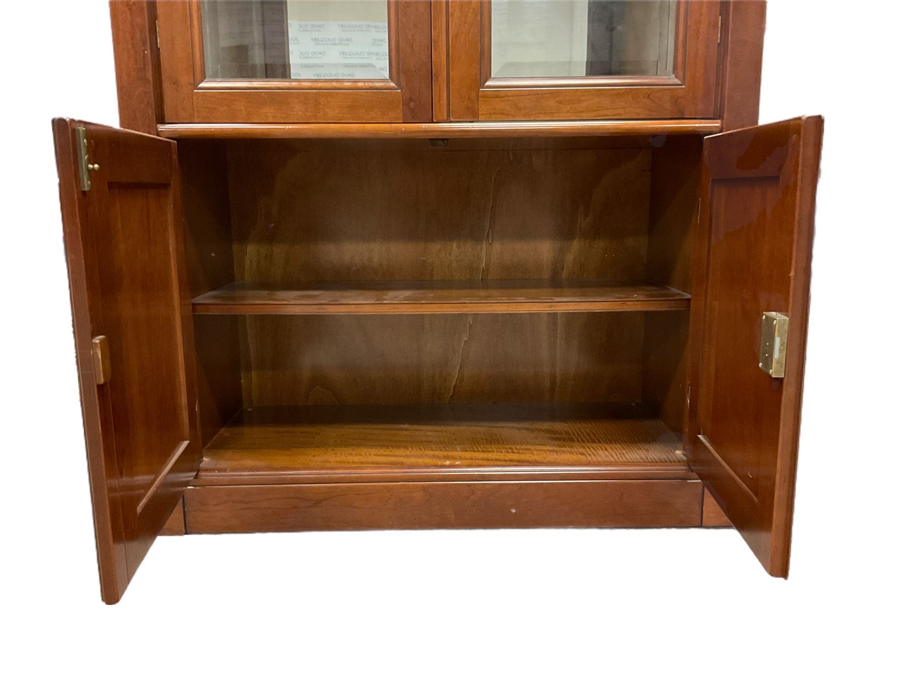Grange Furniture - cherry wood finish display cabinet, two bevel glazed doors enclosing mirrored interior with glass shelves, double panelled cupboard below, on plinth base