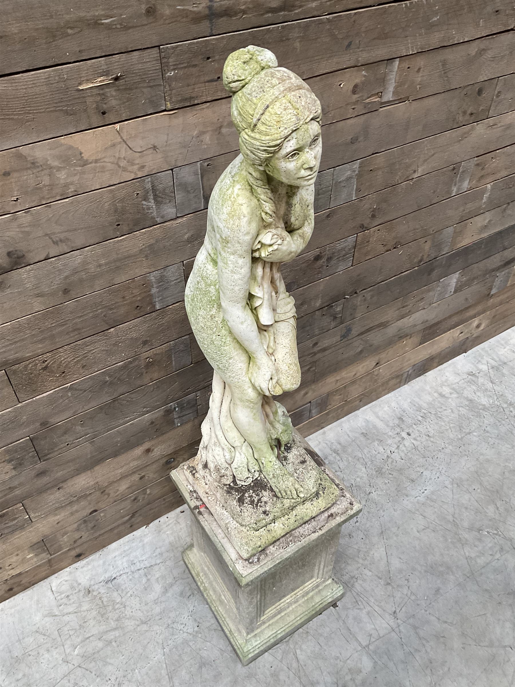 Cast stone garden figure of a bathing lady, raised on square plinth