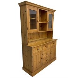 Waxed pine dresser, raised back fitted with two glazed cabinets, the base fitted with five drawers and two cupboards, plinth base