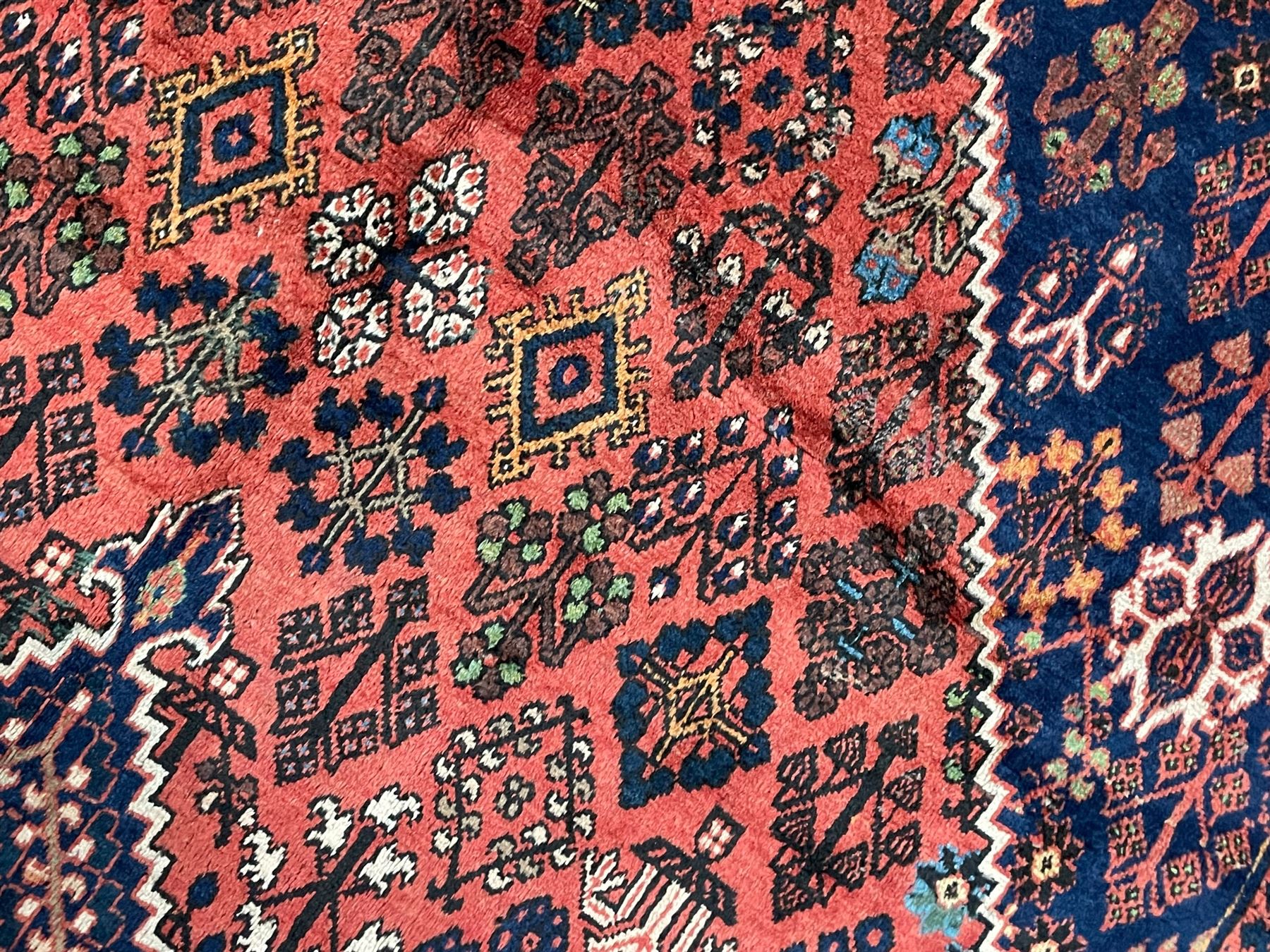 Persian Joshgan red ground rug, the medallion, field and spandrels decorated with clusters of Pitrak and tree of life motifs, the border with repeating design decorated with stylised plant motifs, within guard stripes