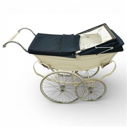 Mid-20th century Osnath pram, the cream painted metal body with navy fabric hood and apron, cream vinyl lined interior fitted with patterned mattress, raised on sprung metal supports with spoked wheels and white rubber tyres