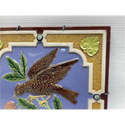 19th century Minton & Co majolica tile, decorated in relief with a bird upon a fruiting branch against a blue ground, with textured ochre border and anthemion to each corner, impressed mark verso, H19.7cm