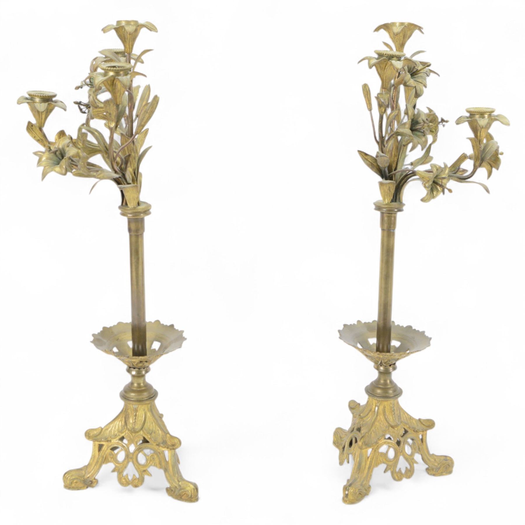 Pair of late 19th century gilt cast candelabra, each with scrolling tripartite base leading to an acanthus detailed circular pan and plain stem, supporting three arms entwined with lily flowers and leaves, the sockets also modelled as lily flowers, H60cm