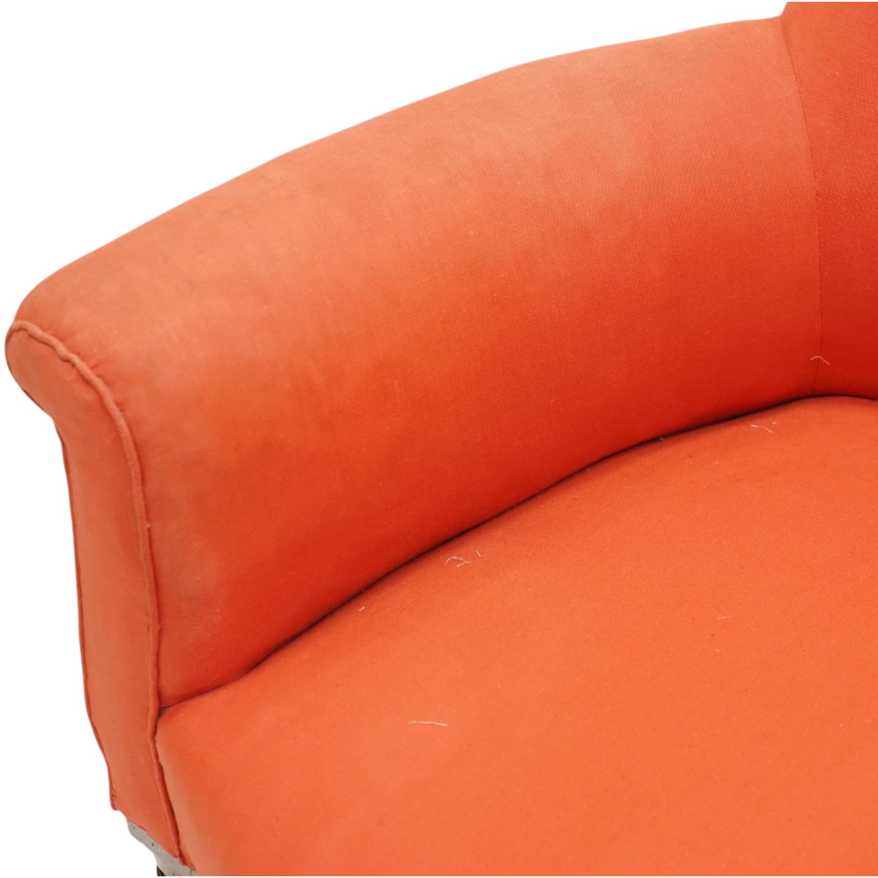 Victorian coral red upholstered armchair, the swept high back above padded arms with rolled fronts, on short turned ebonised front supports with castors