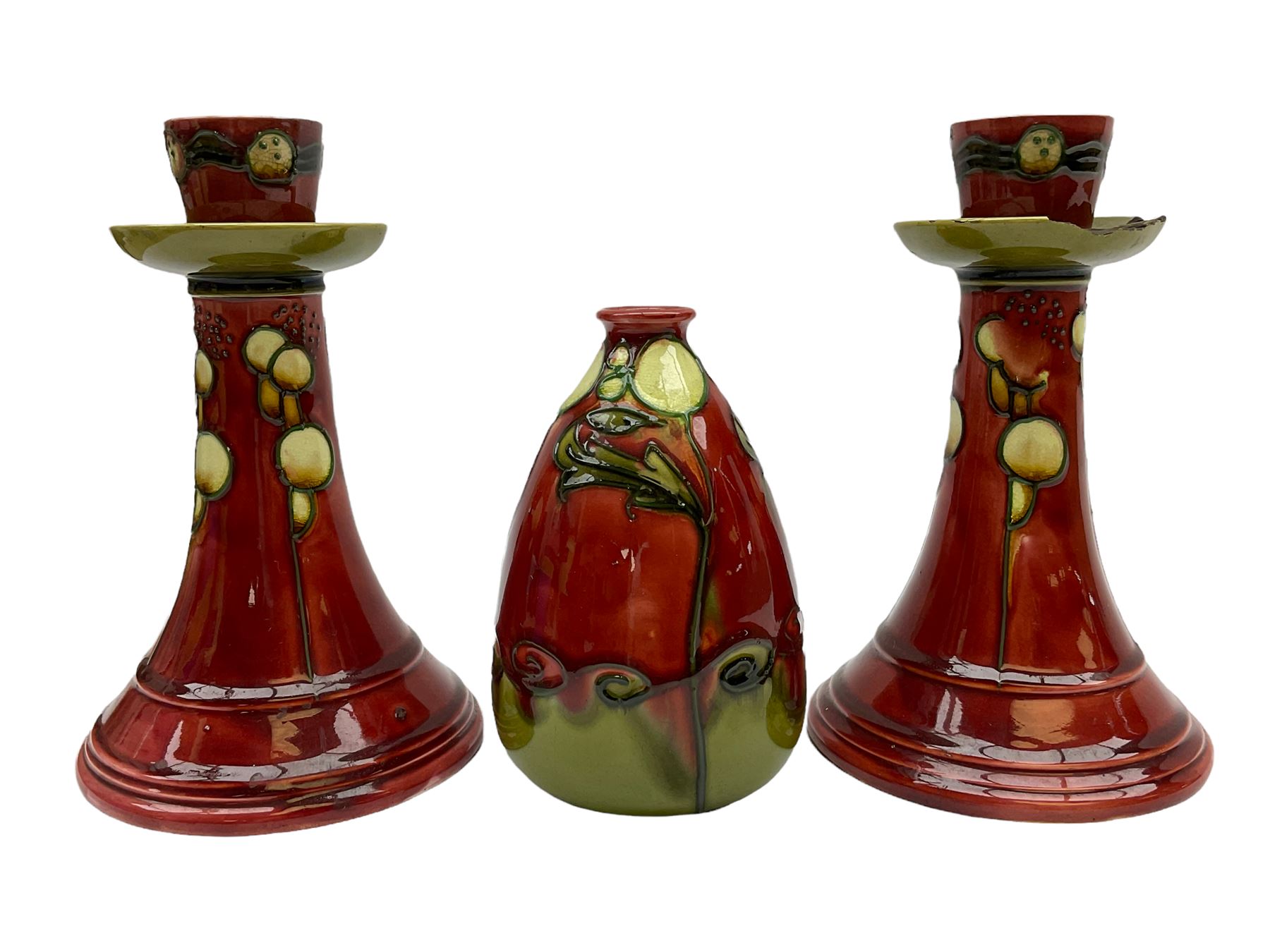 Minton Secessionist vase, with tube-lined stylised flower head decoration upon a red and green ground, printed mark to base 'Minton Ltd, No. 31', together with a matching pair of Minton Secessionist candle sticks, candlestick H17cm