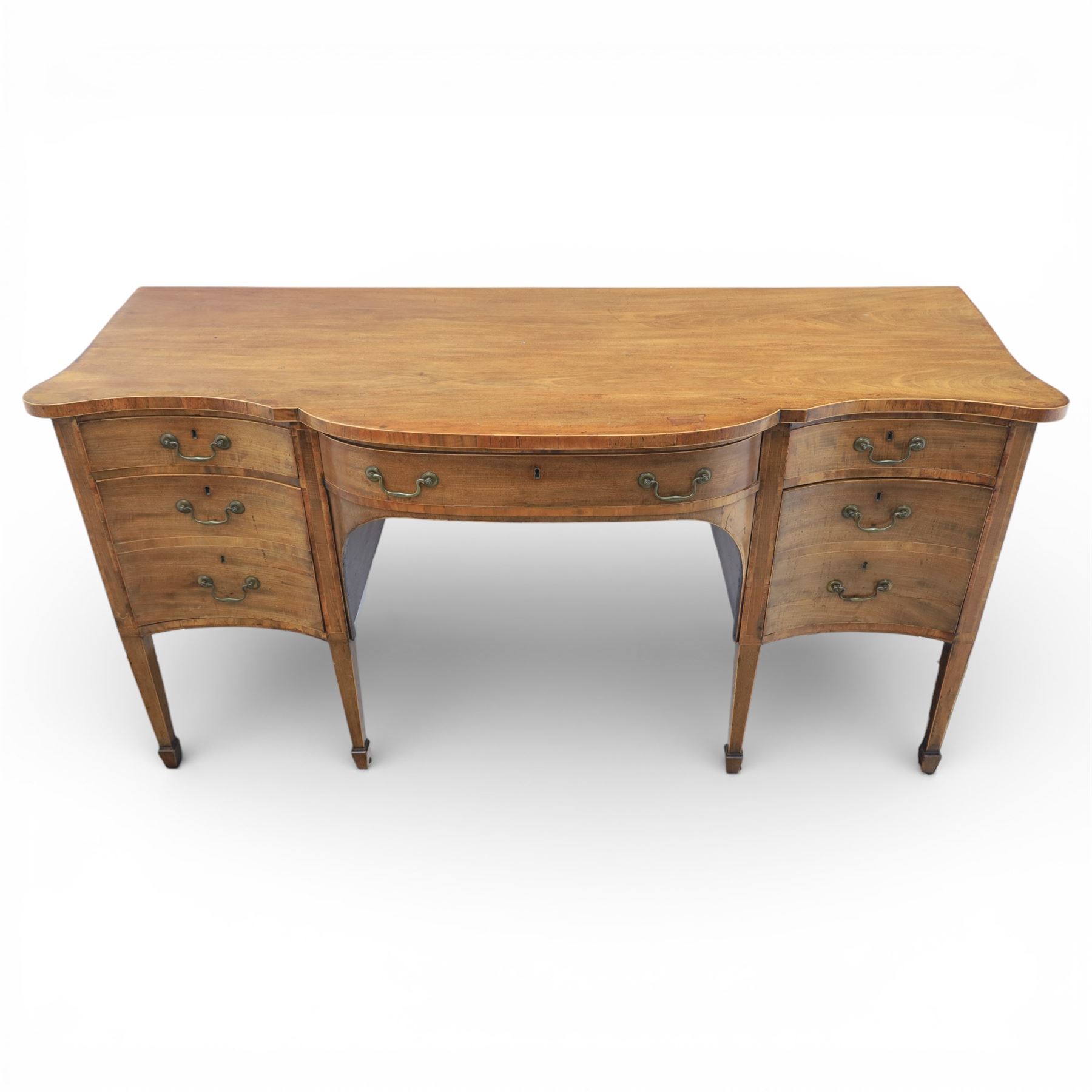 Early 20th century mahogany bow front sideboard, the shaped and moulded top above central kneehole recess with baize lined frieze drawer, flanked by twos drawers either side with the lower drawer double height, raised upon square tapering legs with spade feet