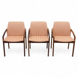 Mid-20th century Danish teak armchairs, each with curved open arms and upholstered seat and backrest in salmon pink striped fabric, raised on tapering legs
