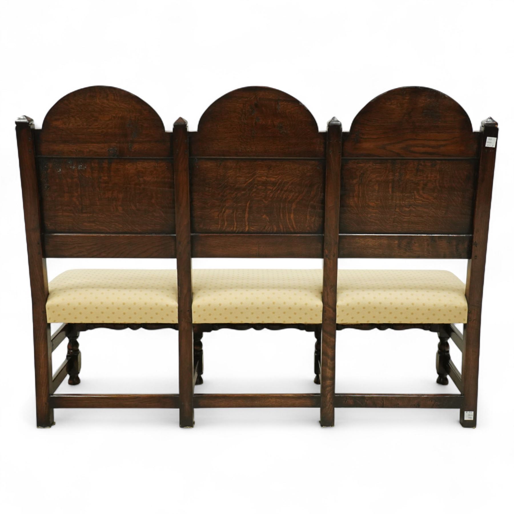 Bylaw of Ross On Wye - 17th-century design oak three-seat hall bench, triple arched panelled back, padded seat upholstered in a yellow herringbone ground fabric with star motif, raised on turned baluster legs united and turned front stretcher