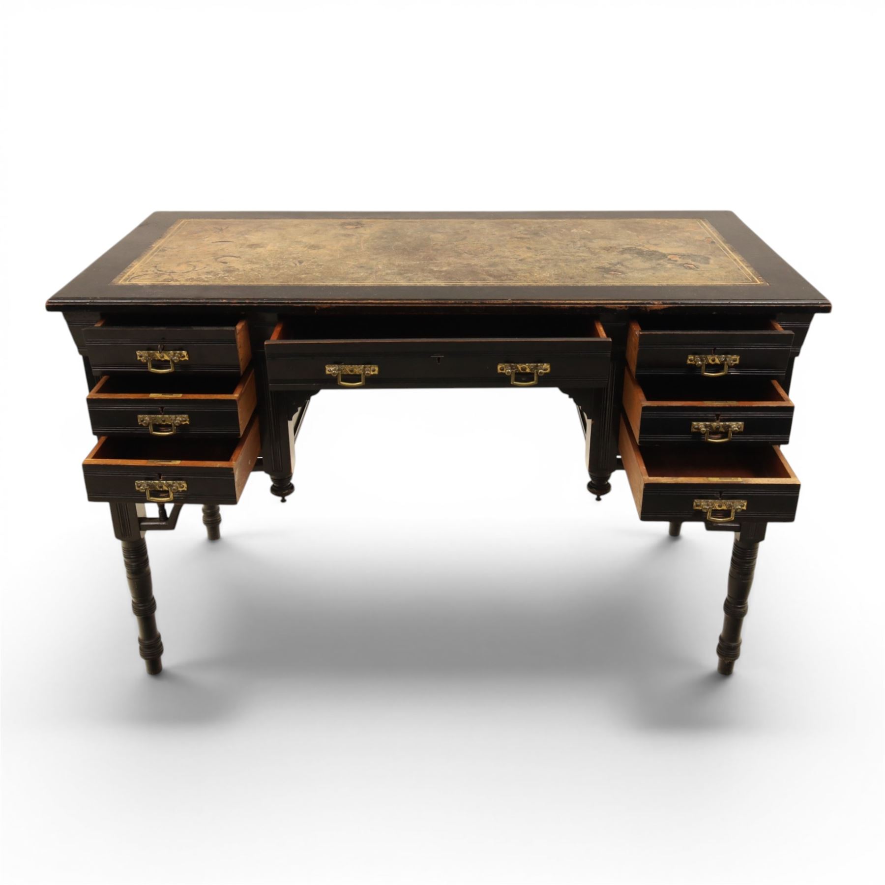 Victorian Aesthetic Movement ebonised writing desk, rectangular top with inset tooled leather, central frieze drawer with pierced spandrels, flanked by two banks of three drawers, brass swing handles, raised on turned supports 