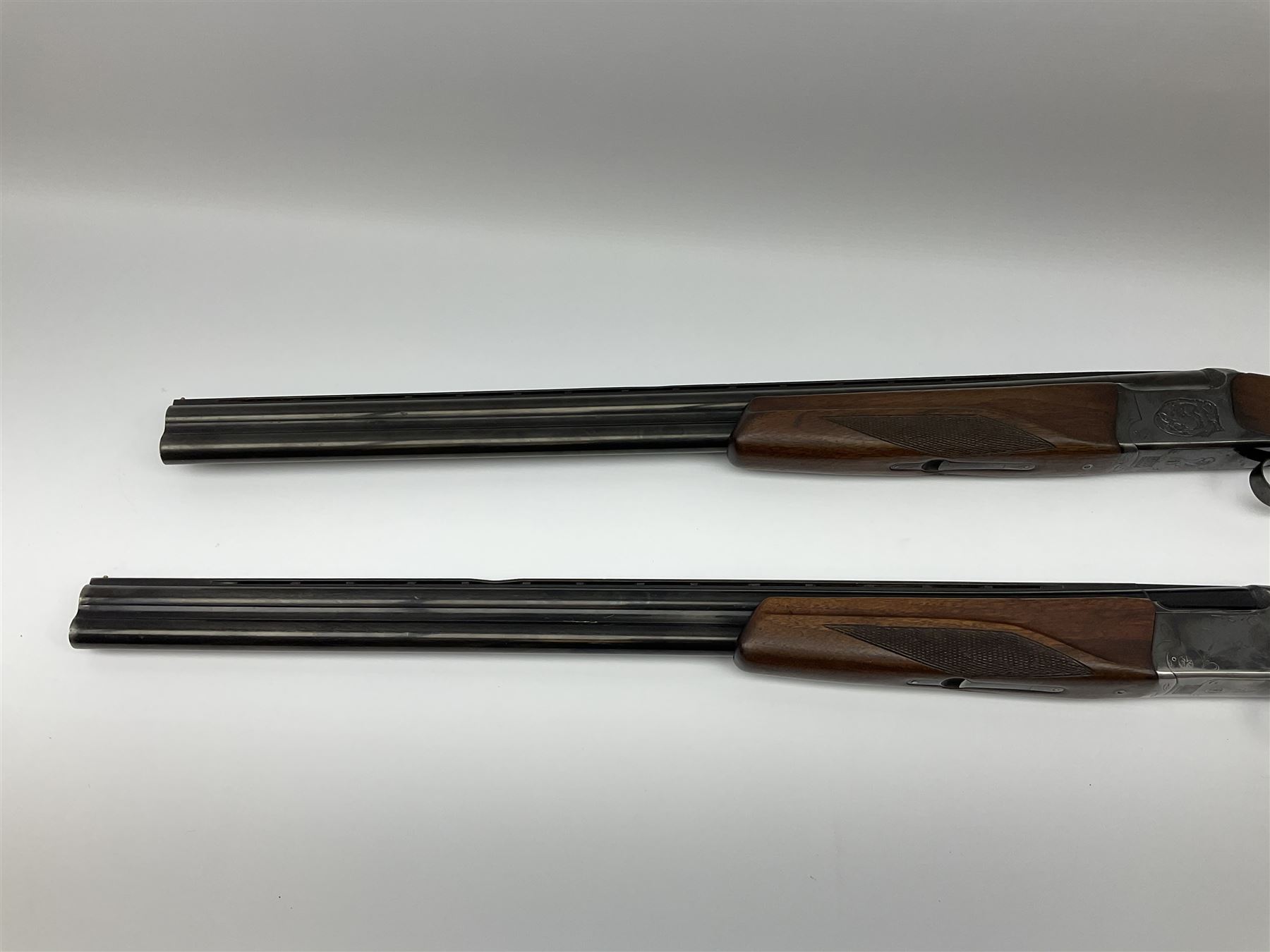 Two Russian Baikal 12-bore over-and-under double barrel boxlock non-ejector sporting guns; one with 68.5cm barrels, walnut stock with chequered pistol grip and fore-end and thumb safety, serial no.520545, L111cm overall; the other with 72.5cm barrels, walnut stock with chequered pistol grip and fore-end and thumb safety, serial no.012448, L114.5cm overall (2) SHOTGUN CERTIFICATE REQUIRED