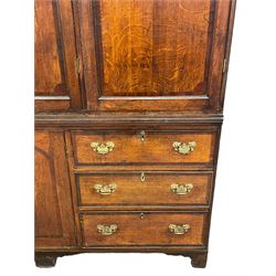 Large George III oak and mahogany banded housekeepers cupboard, projecting cornice over fretwork decorated frieze, three panelled doors enclosing small drawers and shelves, the lower section fitted with six drawers and central cupboard, on bracket feet