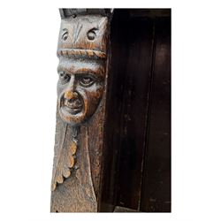 Victorian carved oak corner bookcase, L-shaped form, moulded top over lunette carved frieze, decorated with S-scroll and mask carved corbels with trailing acanthus leaves, fitted with adjustable shelves, on moulded plinth base 