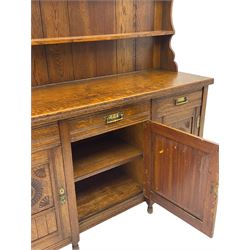 Late Victorian oak dresser, plate rack over three drawers and three cupboards, the panelled doors carved with floral motifs