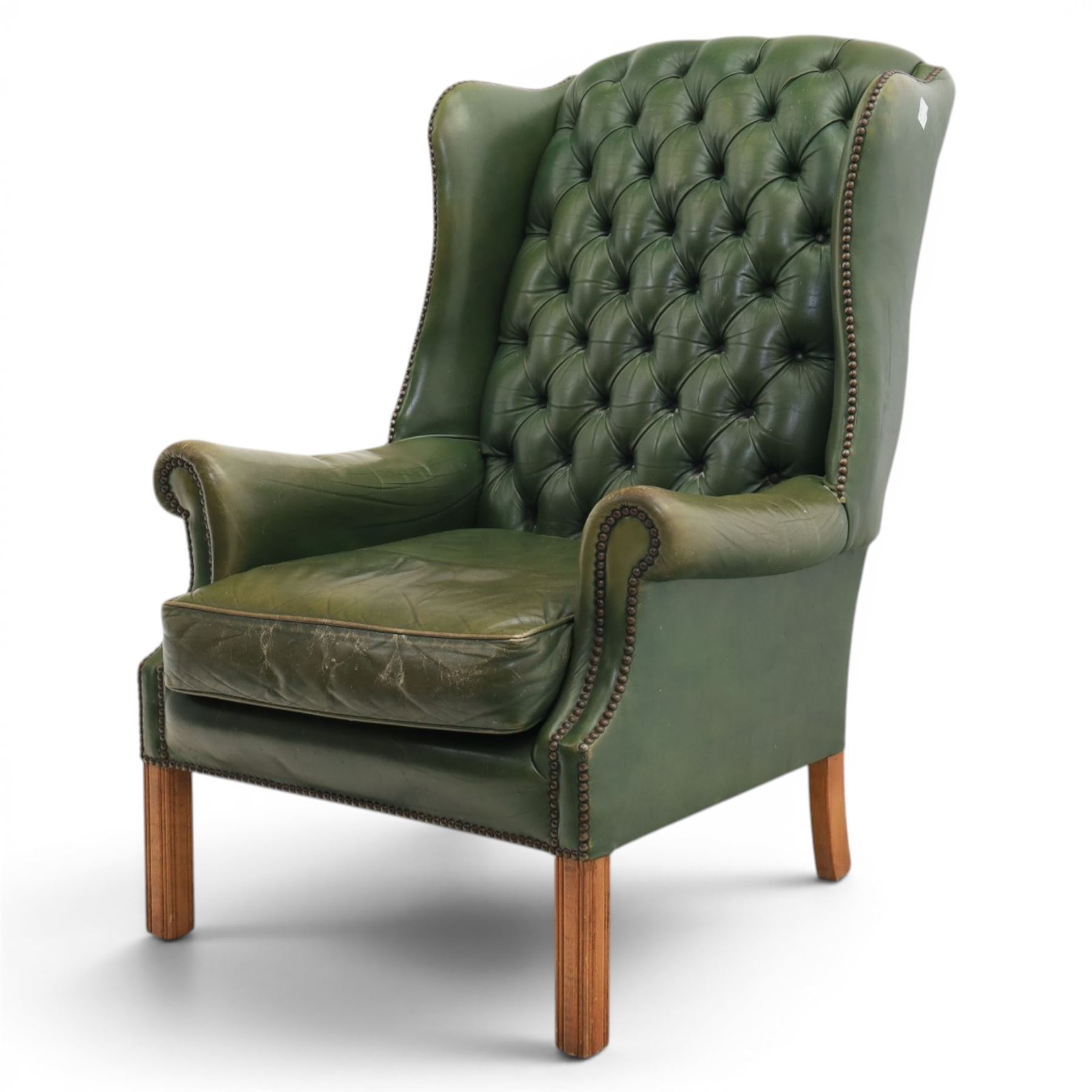 20th century green leather wingback button backed armchair, brass studded trim, with scrolled arms raised on oak supports