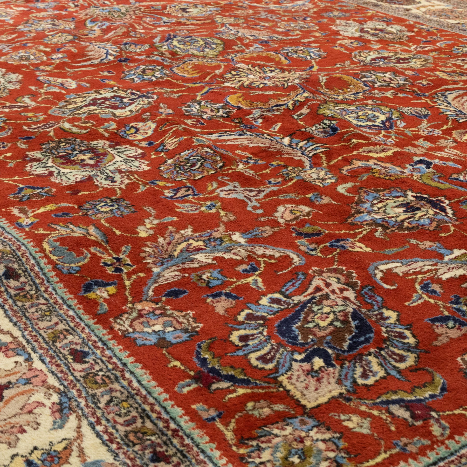 Persian Tabriz hand-knotted carpet, crimson field densely decorated with scrolling floral and foliate motifs, enclosed by a broad cream principal border with repeating floral medallions and multiple guard stripes