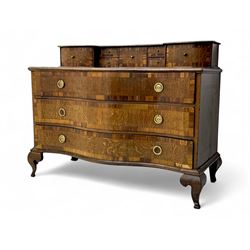 Late 19th century continental oak commode, serpentine fronted with parquetry and crossbanded decoration, the raised superstructure back fitted with a central bank of five recessed drawers flanked by concave drawers, above three full-width drawers with brass ring handles, raised on cabriole supports