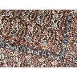 Persian Kirman carpet, the ivory ground field and border decorated with repeating Boteh motifs, interspaced with all-over floral design, blue ground border guards, the top border with signature panel