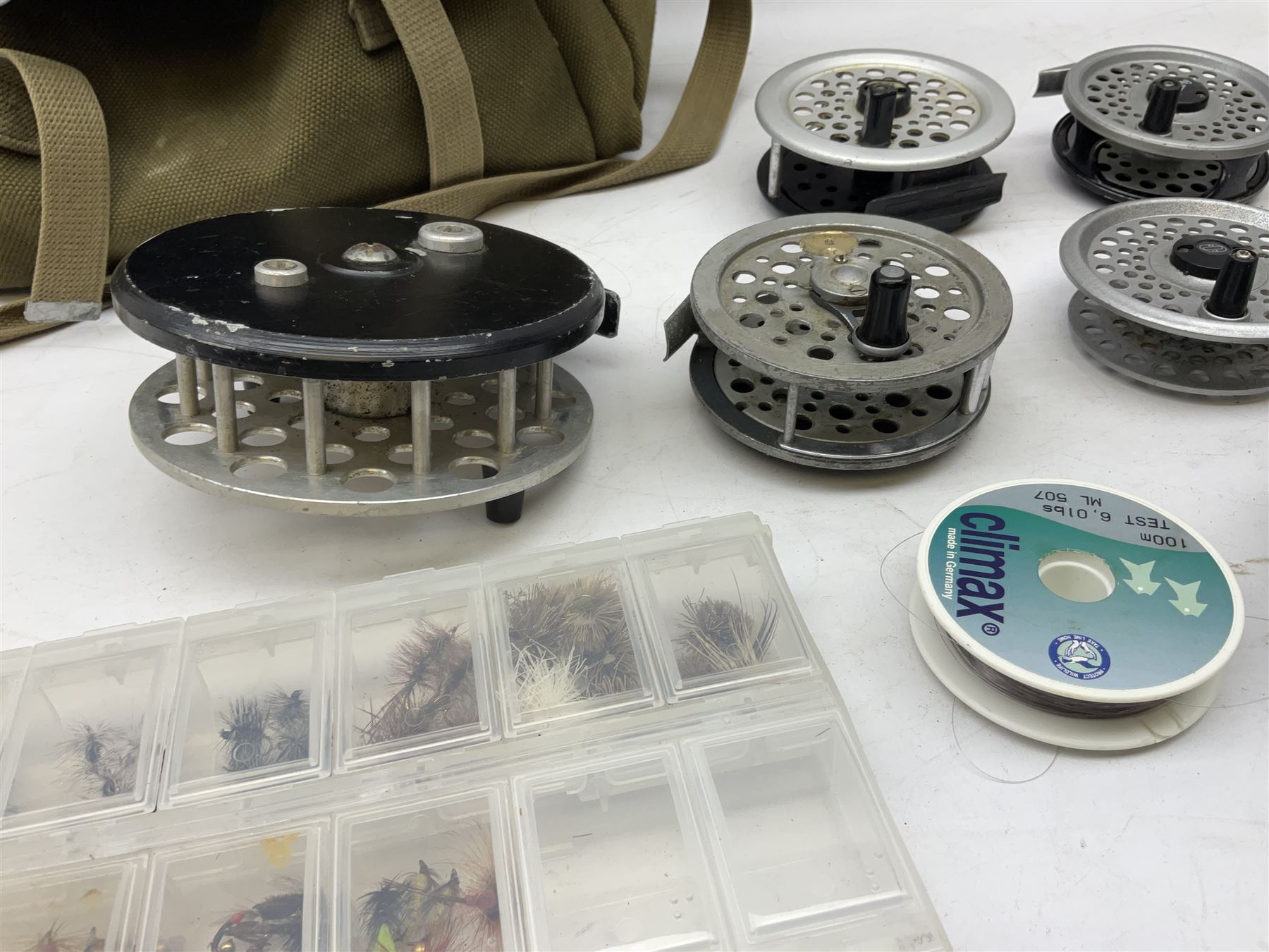 Fishing tackle, including 'The Gnat' fly reel, Alvey 4 1/2 inch reel, Paramount 4 1/2 inch reel, other fishing reels, various fishing flies and other similar items in a carry bag 