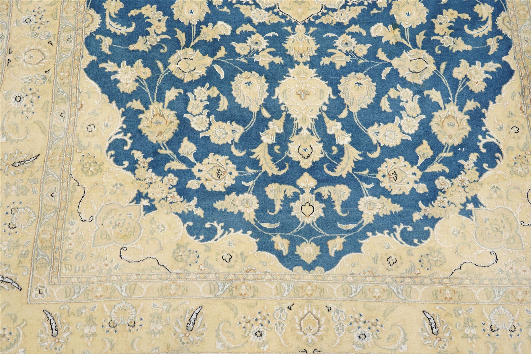 Central Persian Nain hand-knotted rug, sky blue field, with a central cusped medallion in ivory and soft camel tones, issuing an elegant arrangement of scrolling arabesques, palmettes and flowering vines, conforming ivory spandrels, principal pale border decorated with floral sprays and palmettes, flanked by narrow ground borders, with cotton fringe ends  