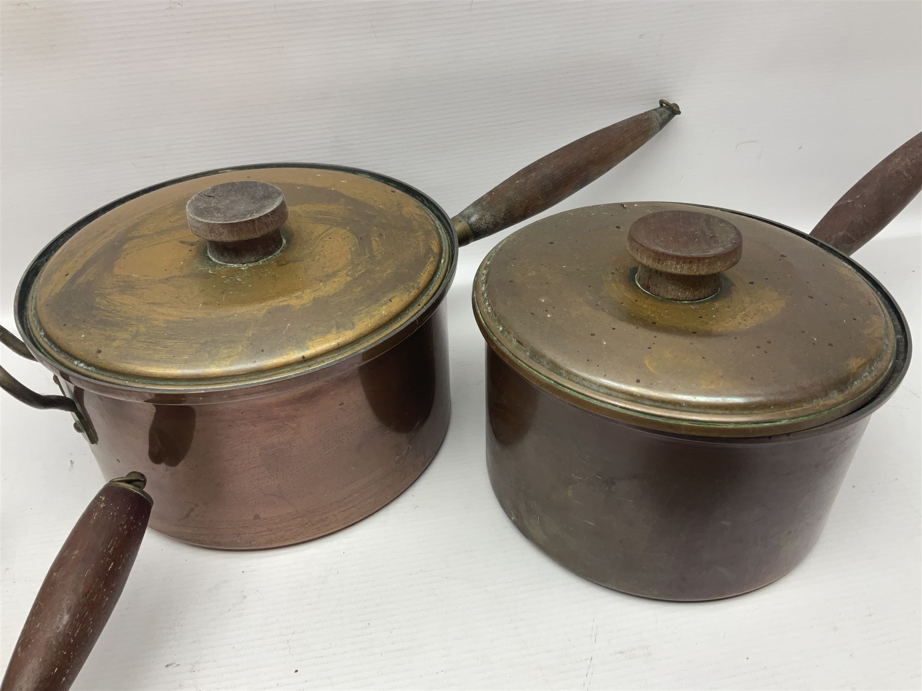 Four Victorian copper moulds, together with a graduating set of copper pans with wooden handles and finials to covers, largest pan 