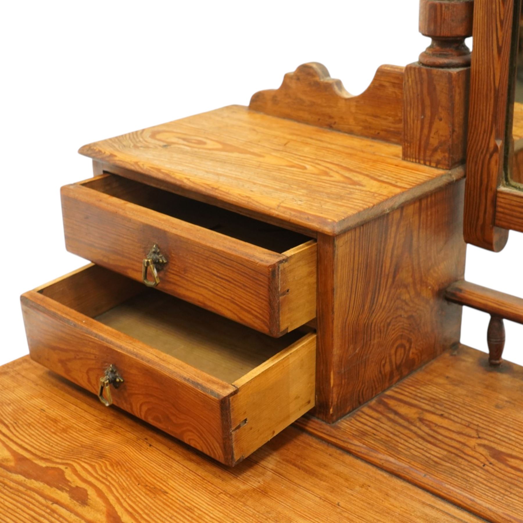 Victorian stripped pine dressing table, rectangular top over two drawers with brass handles, the raised back fitted with adjustable rectangular mirror, spindle gallery flanked by two short jewellery drawers either side, on turned legs