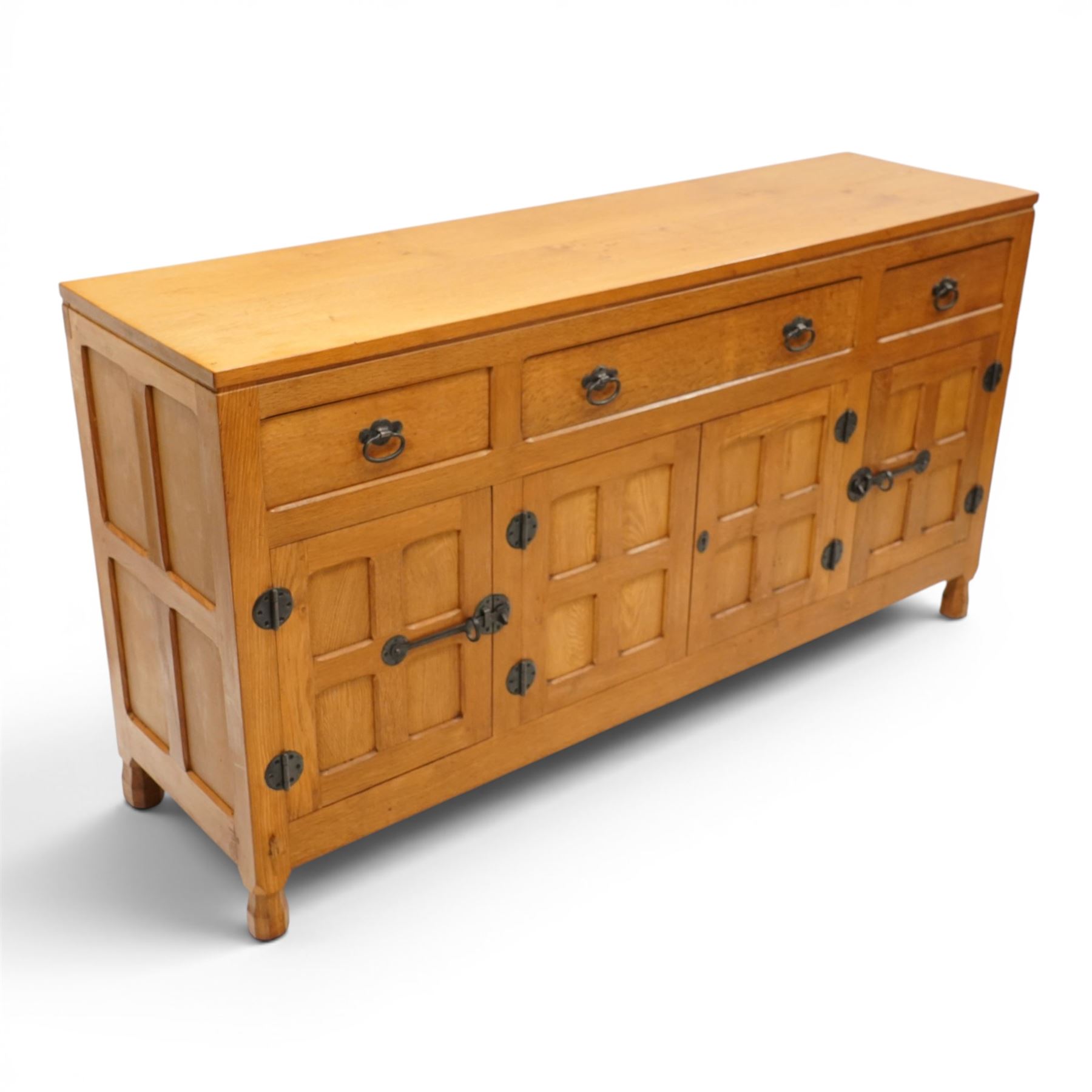 Lizardman - oak 5' sideboard, rectangular top over three panelled frieze drawers, fitted with two double panelled cupboards with wrought iron handles and locks, raised on tapered octagonal feet, with carved lizard signature, by Derek Slater of Crayke