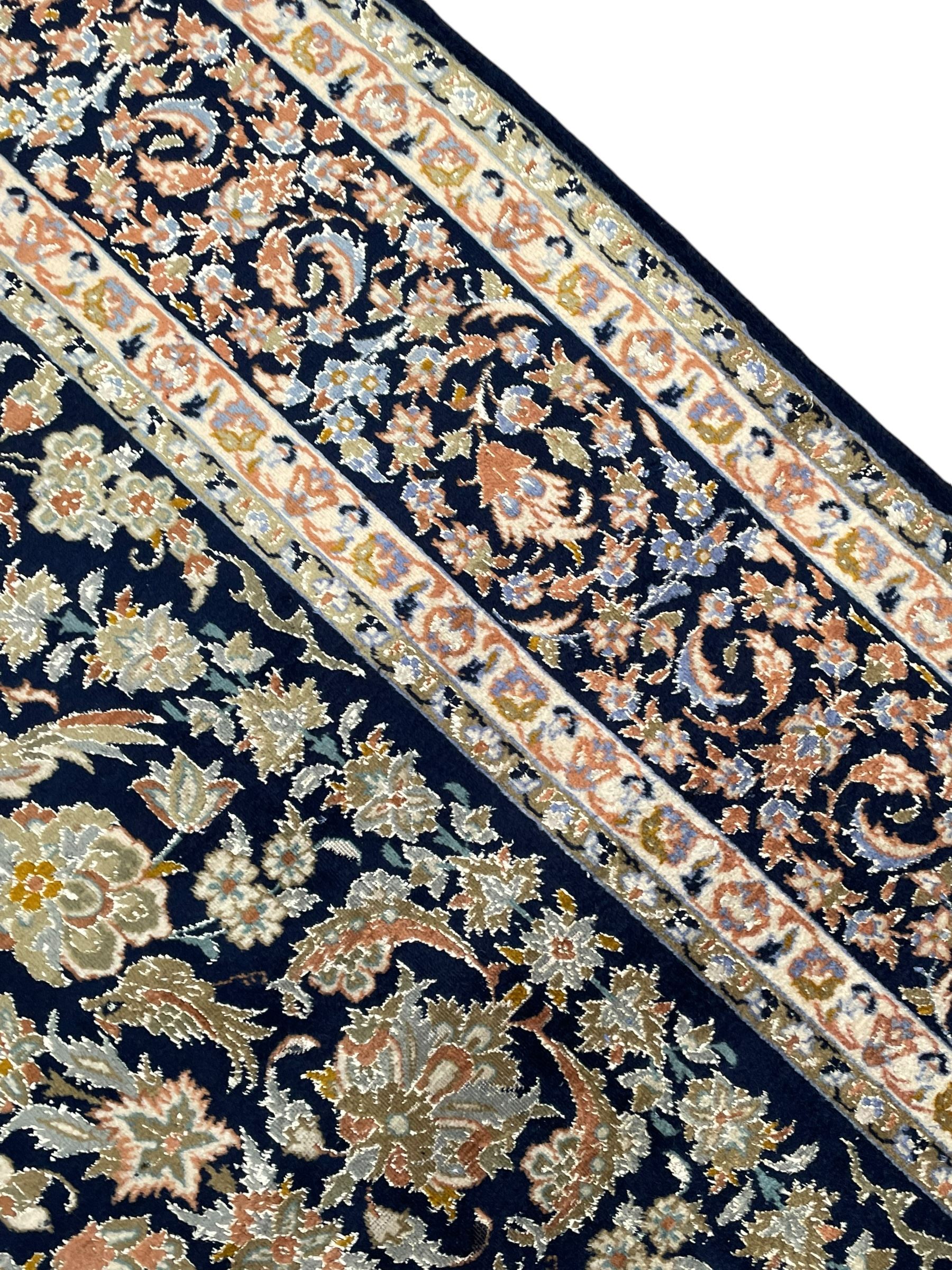 Persian Kashan indigo ground rug, the field consisting of trailing flower head bands and leafy branches, decorated with kuş or bird motifs, the border with repeating border containing curling leaves and flower heads, within guard bands 