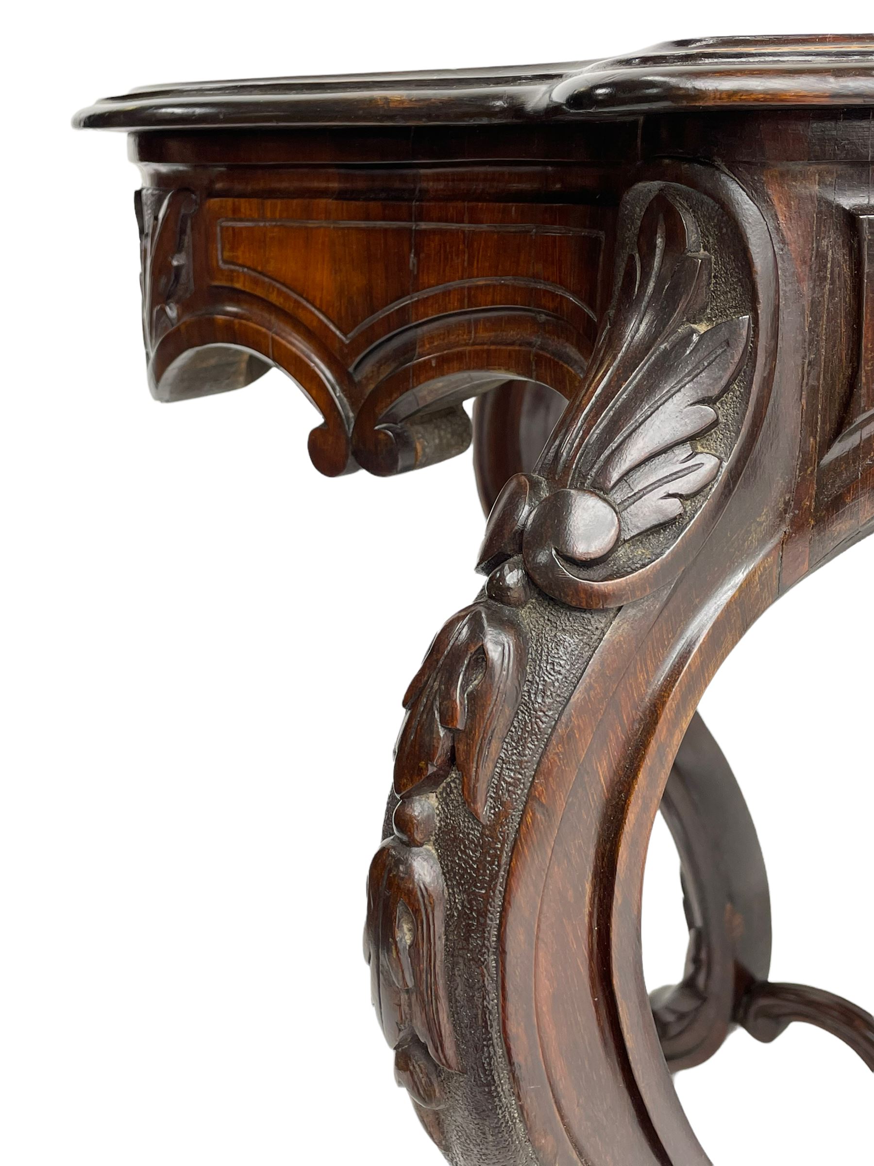 19th century Irish rosewood centre table, the shaped and moulded top over shaped apron carved with scrolled foliage, on serpentine supports carved with bell flowers, the supports united by anthemion carved finial and s-scroll x-framed stretchers